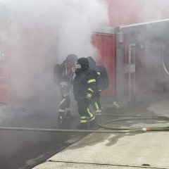 Kameraden vor dem rauchenden heißen Container