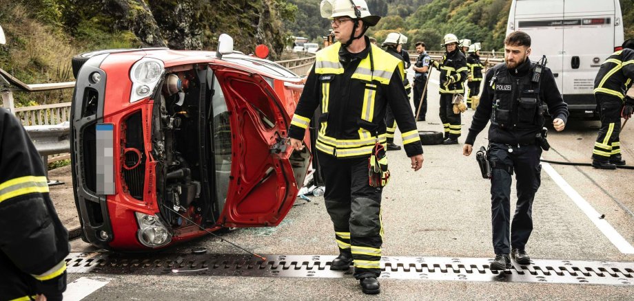 Verunfallter Pkw auf der Seite liegend und Einsatzkräfte